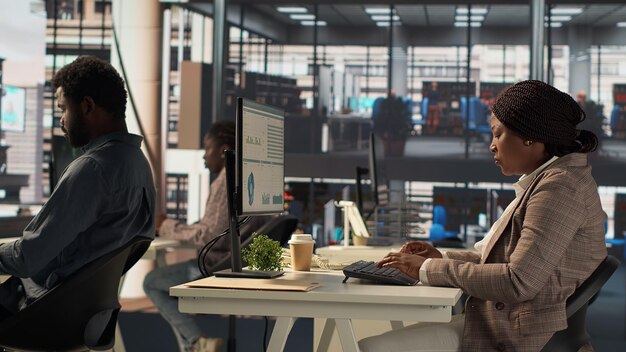 Skilled female investor working on financial forecasts at her workstation