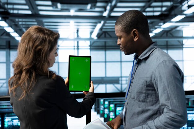 Team of technician in data center using green screen mockup tablet