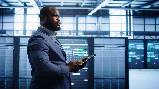 Technician walking in server room doing checkup inputting data on tablet