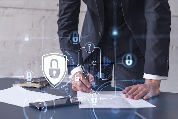 A businessman in formal wear signing the contract to prevent probability of risks in cyber security Padlock Hologram icons over the working desk