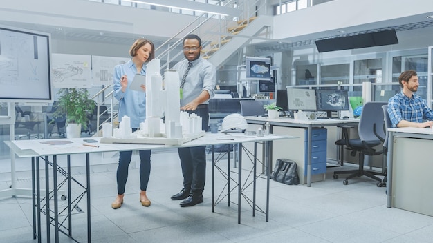 A man and woman stand in front of a table with a model of a city.