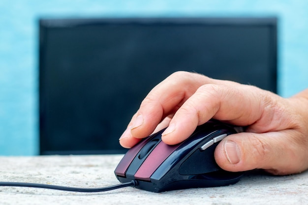 A man's hand on a computer mouse near a computer Entering data on a computer using a mouse