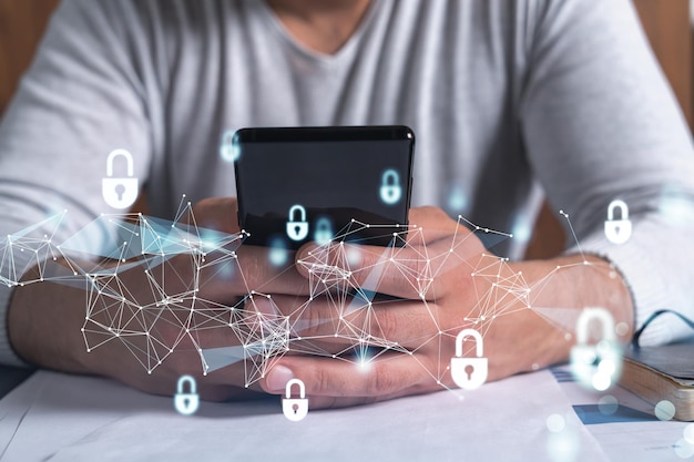 a programmer is browsing the internet in smart phone to protect a cyber security from hacker attacks and save clients confidential data padlock hologram icons over the typing hands