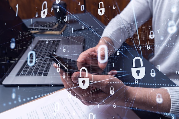A programmer is browsing the Internet in smart phone to protect a cyber security from hacker attacks and save clients confidential data Padlock Hologram icons over the typing hands