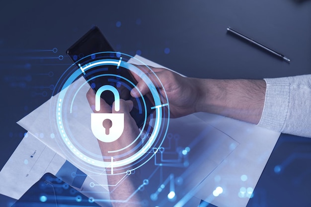 A programmer is browsing the Internet in smart phone to protect a cyber security from hacker attacks and save clients confidential data Padlock Hologram icons over the typing hands