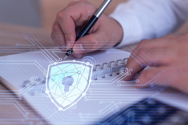 A programmer is taking notes of clients needs to protect cyber security from hacker attacks and save clients confidential data Padlock Hologram icons over the typing hands Formal wear