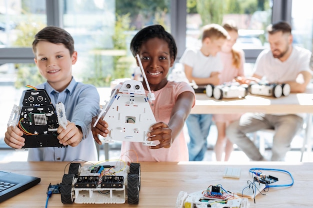 Adorable pre-teen kids inspecting robotic vehicle workshop
