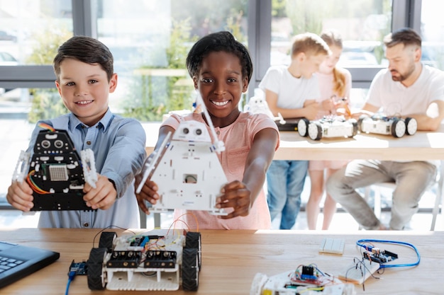 Adorable pre-teen kids inspecting robotic vehicle workshop