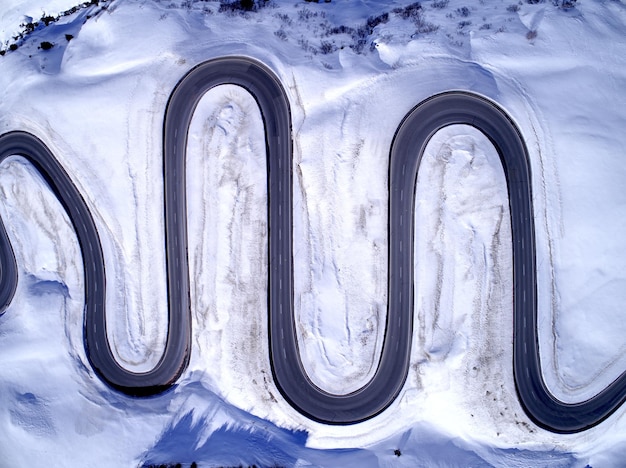Aerial view of winding road amidst snow covered field during winter