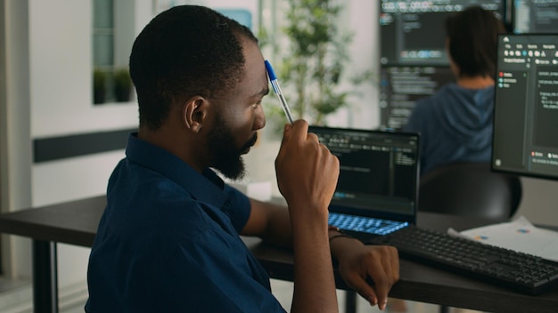 african american system engineer thinking about html script development to code it language in agency office. software developer brainstorming ideas to write artificial intelligence algorithm.
