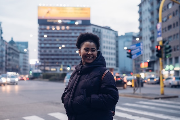 African and curly girl smiling in the street