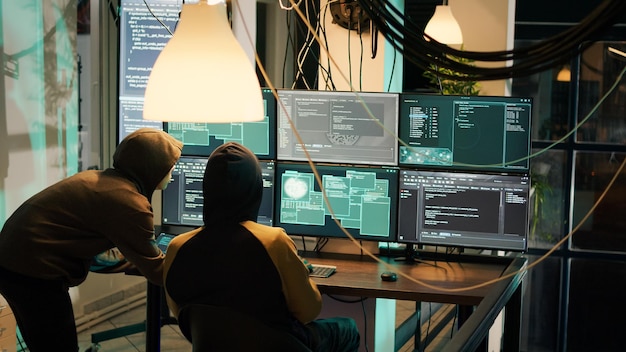 Anonymous people planting virus to exploit computer server, hacking network system late at night. Cyber spies working with web encryption to hack software and break security firewall.