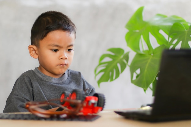 Asian boy students learn at home in coding robot cars and electronic board cables in STEM STEAM mathematics engineering science technology computer code in robotics for kids concept