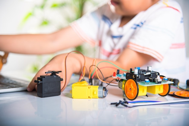 Asian kid boy learns coding and programming with laptop for Arduino robot car