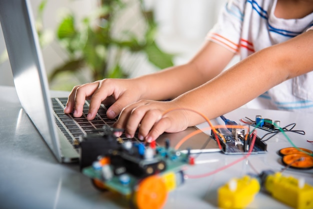 Asian kid boy learns coding and programming with laptop for Arduino robot car