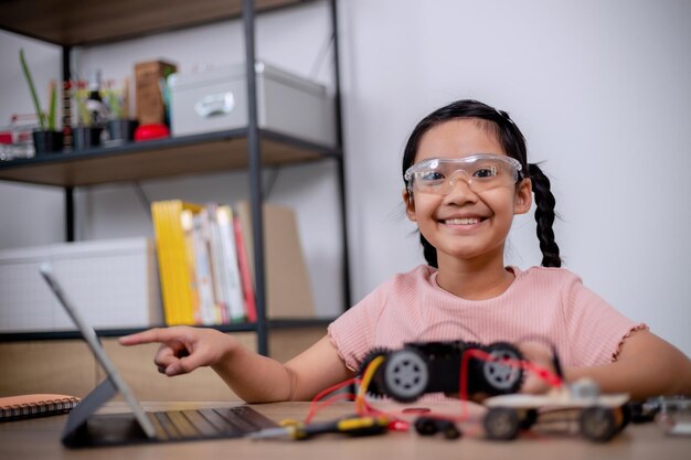 Asian students learn at home by coding robot cars and electronic board cables in STEM STEAM mathematics engineering science technology computer code in robotics for kids concepts