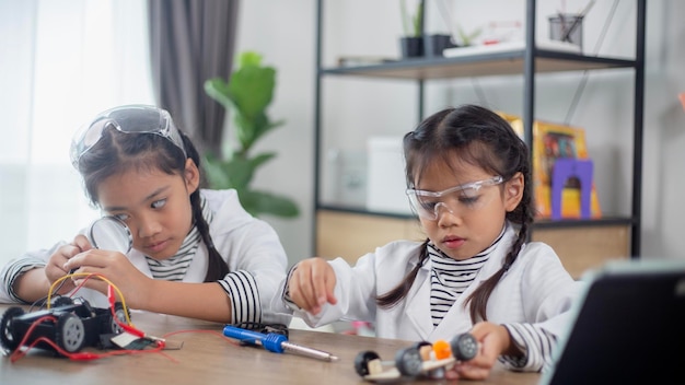 Asian students learn at home in coding robot cars and electronic board cables in STEM STEAM mathematics engineering science technology computer code in robotics for kids concept