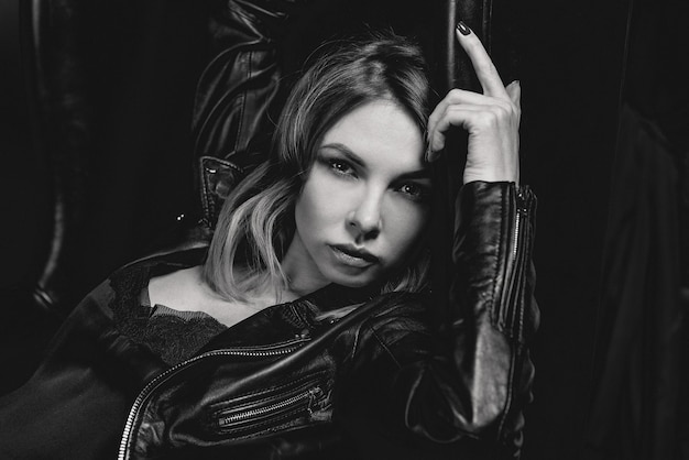 attractive stylish blonde woman in silk dress and black jacket on the dark background