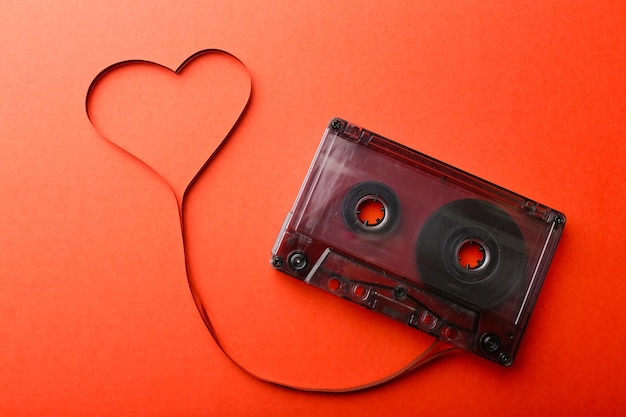 Audio cassette with magnetic tape in shape of heart on red background