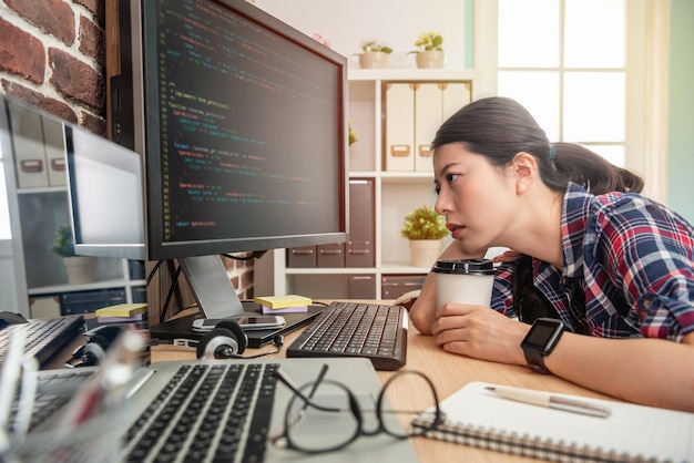 beautiful female programmer feeling exhausted and holding coffee trying to stay awake.
