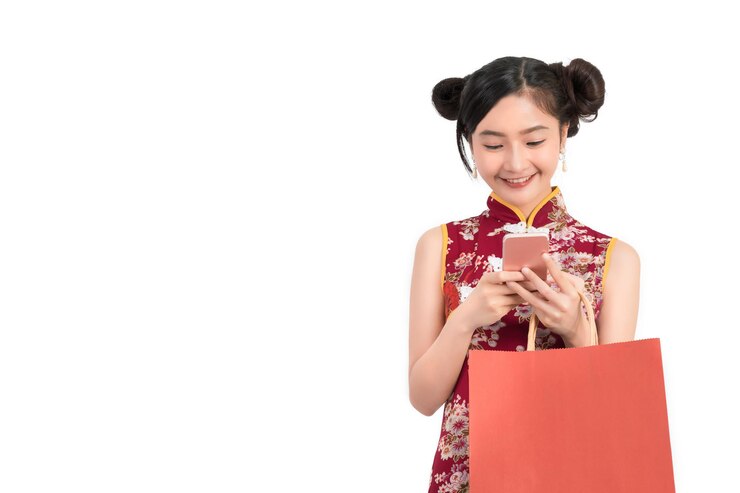 Photo beautiful woman in chinese dress using smart phone while carrying shopping bag against white background