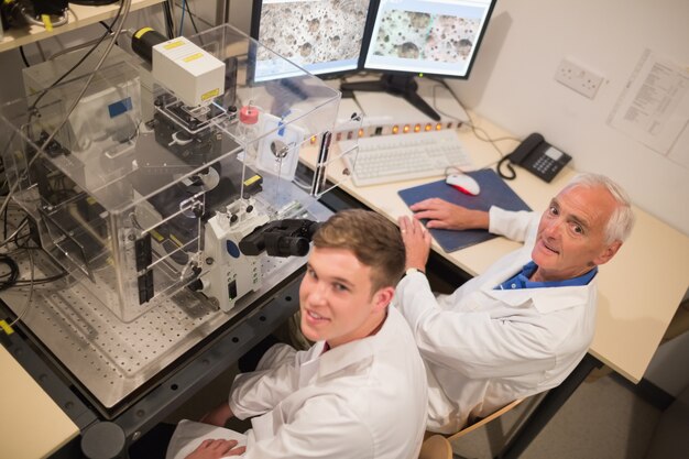 Biochemist and student looking at microscopic images on computer