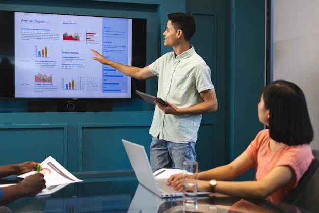 Biracial man presenting to diverse group in a modern business office Asian woman listening
