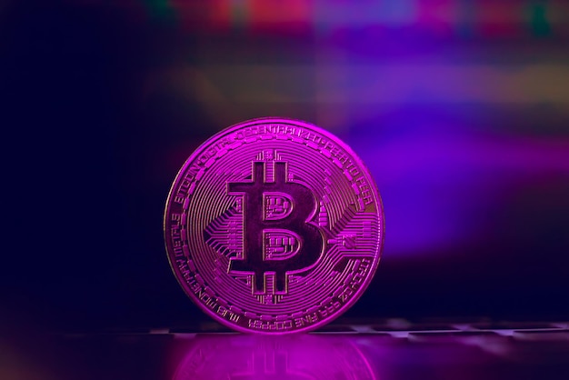 Bitcoin on the background of a graph on a laptop in neon light. Cryptocurrency