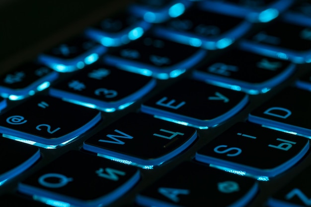 Blue backlight, backlit on gaming laptops computer in the dark. Close up.
