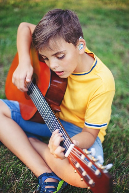 boy playing guitar sitting at park