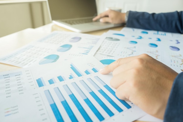 Businessman analyzing graphs and using laptop at desk