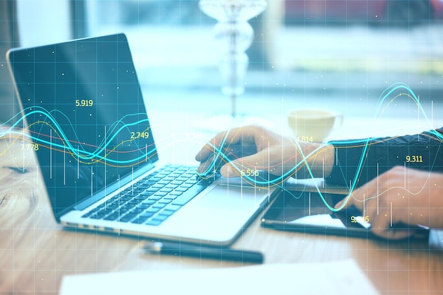 Businessman hands typing on laptop with glowing stock chart