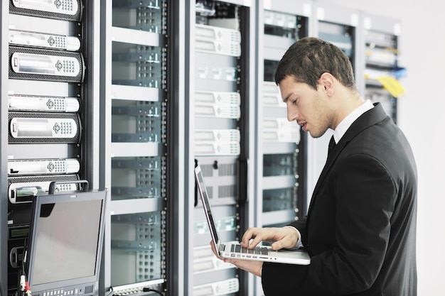 businessman with laptop in network server room