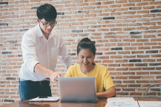 Các doanh nhân thảo luận trước máy tính xách tay trên nền tường gạch