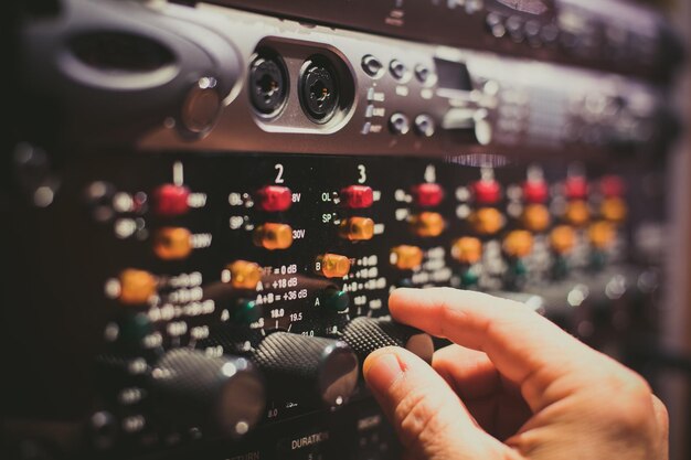 Cận cảnh bàn tay người điều chỉnh núm vặn trên bộ khuếch đại audio