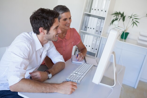 Casual business team working together at desk using computer
