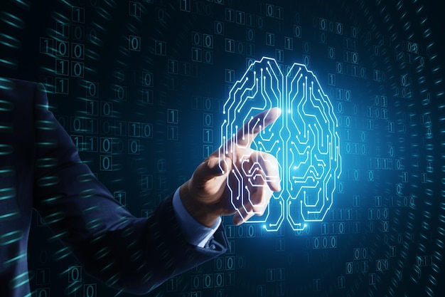 Close up of businessman hand pointing at glowing brain hologram with binary coding on blue background Programming machine learning and artificial intelligence concept