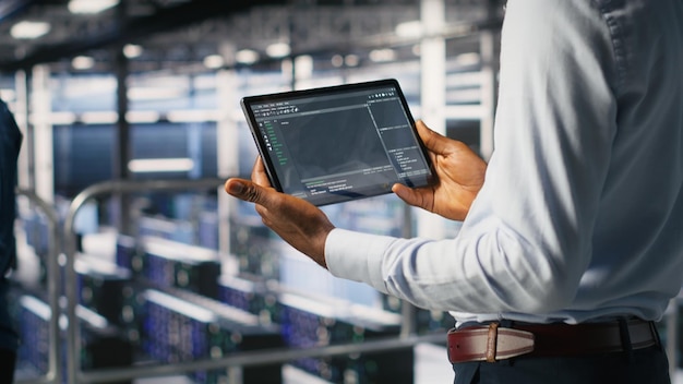 Close up of data center programmer looking at code debugging tools running on tablet server farm it