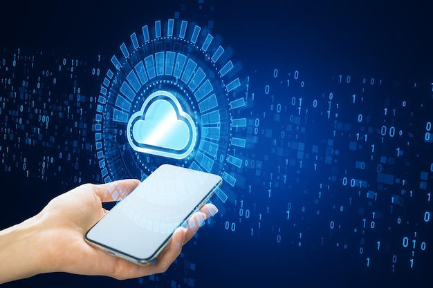 Close up of female hand holding white smartphone with creative glowing cloud computing hologram with binary coding on dark blue background Digital server support and network concept