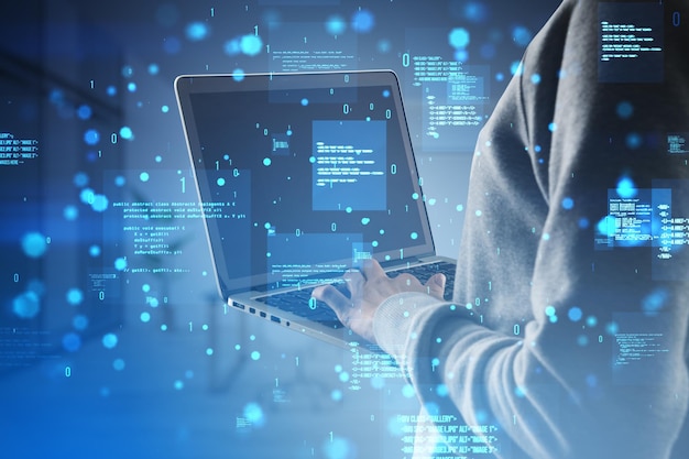 close up of hacker hands using laptop with creative binary coding hologram on blurry background software programming code and hacking double exposure