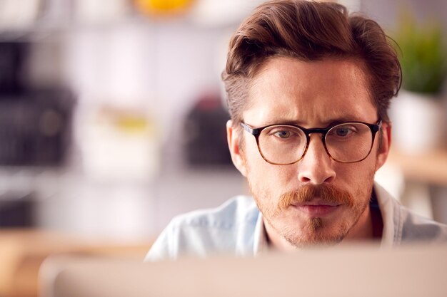 Close Up Of Male Architect In Office Working On Desktop Computer Viewed From Behind Screen