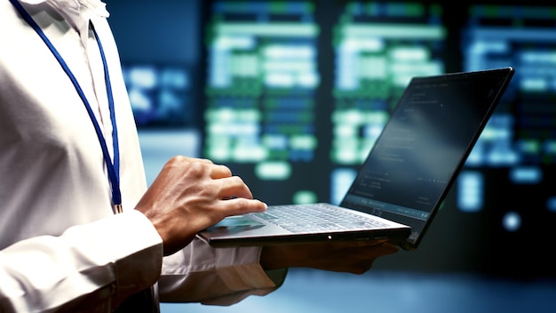Close up of mechanic using laptop to check electronics in blockchain technology application specific integrated circuit server rig rows. Worker checking for issues in cryptocurrency mining farm