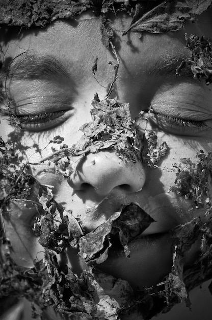 close-up of person face covered with dry leaves