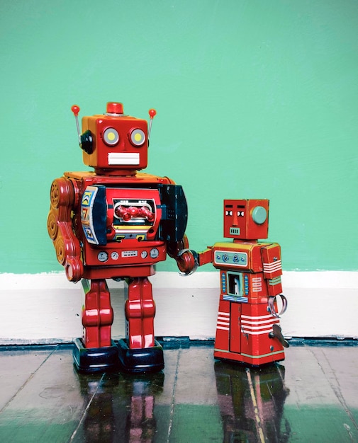 Close-up of red toy robots on floor against wall