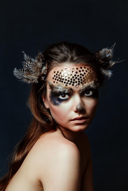 close-up of shirtless young woman with make-up against black background