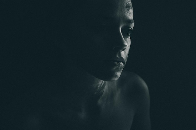 close-up of thoughtful woman with face paint against black background