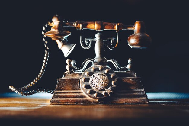Close-up of vintage rotary phone on table against black background