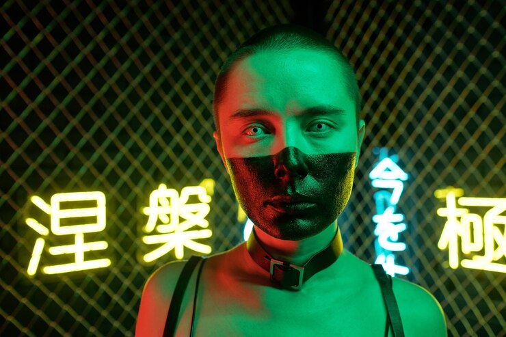 Photo close-up of young cyberpunk woman with face painted with black color looking at camera against the neon hieroglyphs meaning nirvana and western paradise