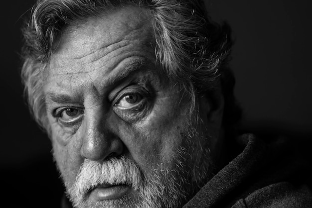close-up portrait of senior man against black background