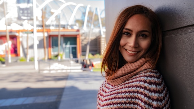 close-up portrait of woman smiling while standing against wall
